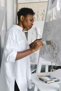 woman painting with brush on easle