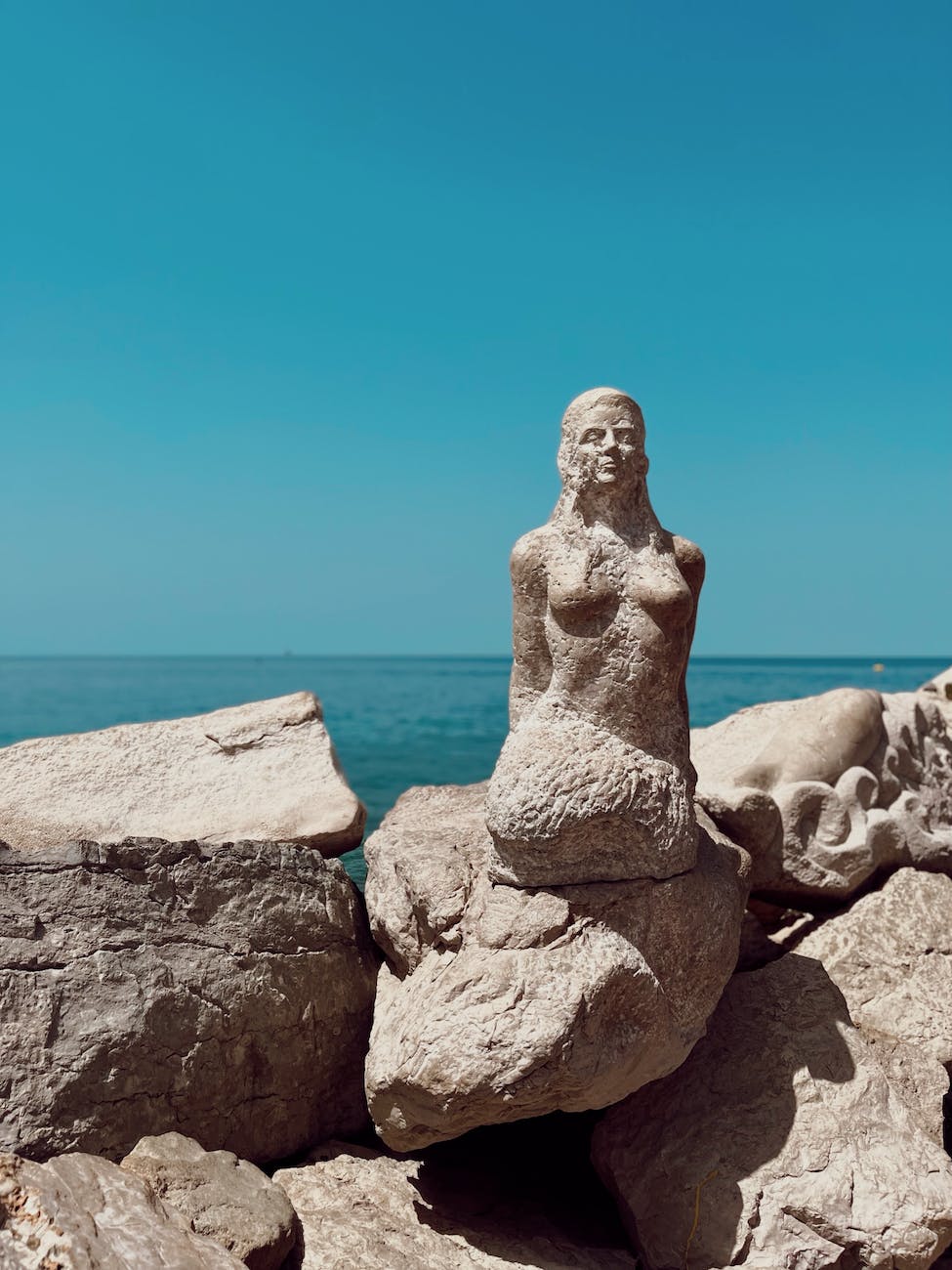 sculpture of siren on rocks on sea shore